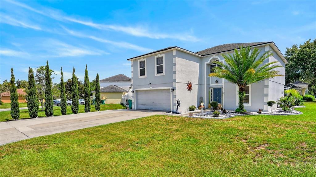 A two-story house with a gray stucco exterior, a two-car garage, and a palm tree — 600 BRIARCLIFF ROAD, EUSTIS, FL