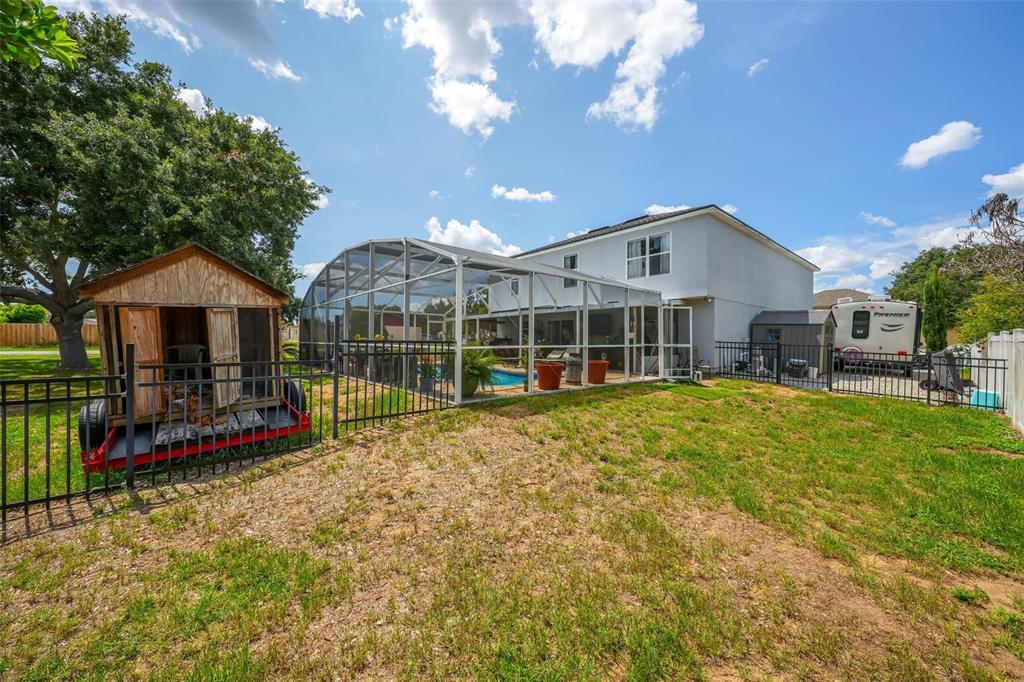 A backyard features a screened-in pool, a wooden shed on a trailer, and a house — 600 BRIARCLIFF ROAD, EUSTIS, FL