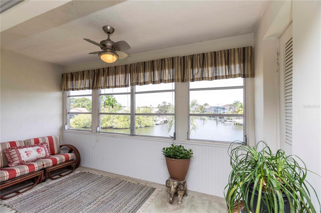 An exterior view of a covered apartment balcony with a dark screen door and windows — 4609 MARINE PARKWAY UNIT 203, NEW PORT RICHEY, FL