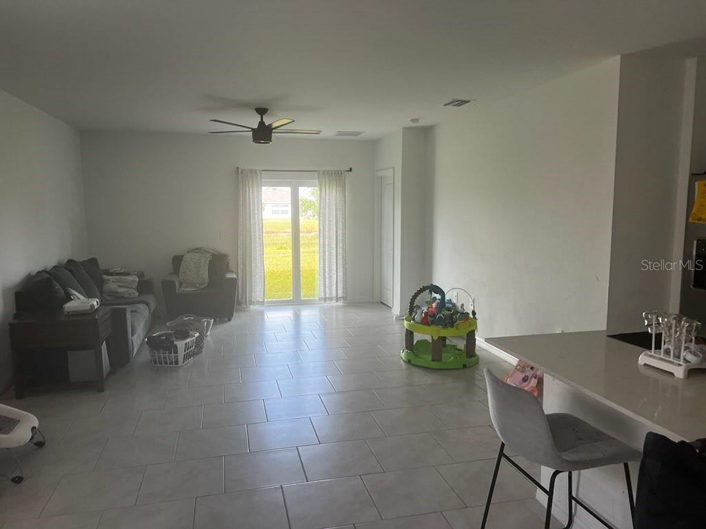 A living room with tile flooring, a ceiling fan, and a sliding glass door — 12170 DAKOTA RIDGE PLACE, LEHIGH ACRES, FL