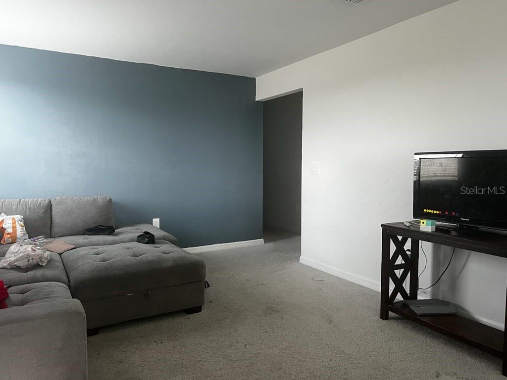 A living room features a gray sectional sofa, a television on a stand, and carpeted flooring — 12170 DAKOTA RIDGE PLACE, LEHIGH ACRES, FL
