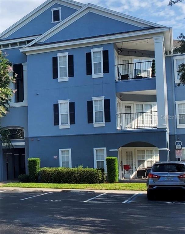 A three-story blue apartment building features balconies, dark shutters, and a ground-level parking area — 3621 CONROY ROAD UNIT 720, ORLANDO, FL