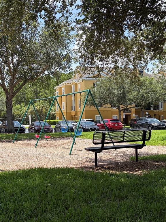 A playground with a swing set and a bench sits in front of an apartment building — 3621 CONROY ROAD UNIT 720, ORLANDO, FL