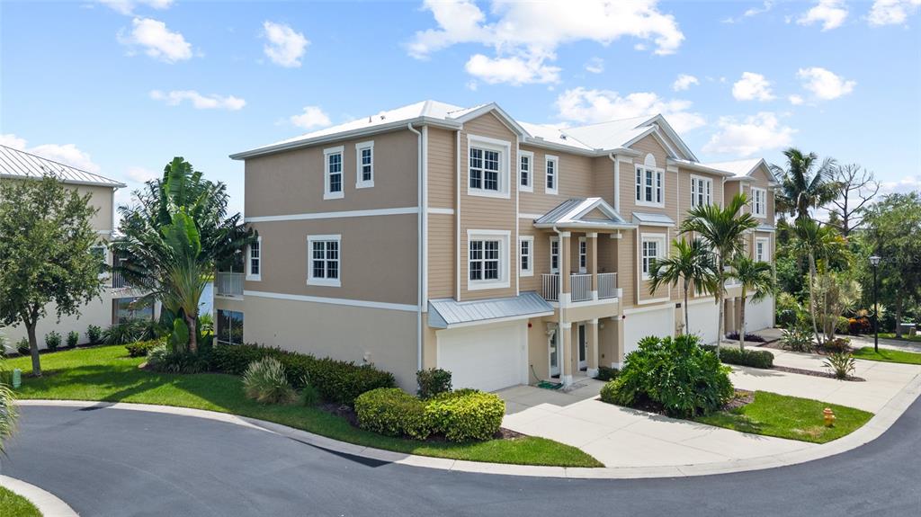 A multi-story tan townhouse with a white garage and palm trees on a sunny day — 10311 LANDS END CIRCLE UNIT 16, PLACIDA, FL