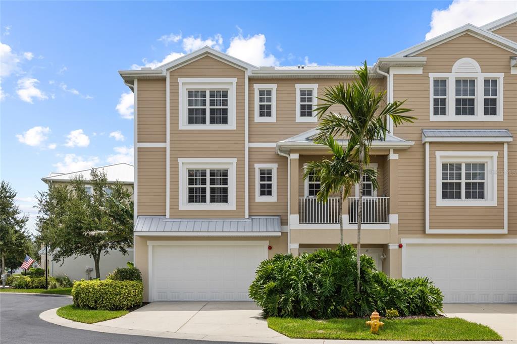 A three-story tan townhouse with a two-car garage and a second-floor balcony — 10311 LANDS END CIRCLE UNIT 16, PLACIDA, FL
