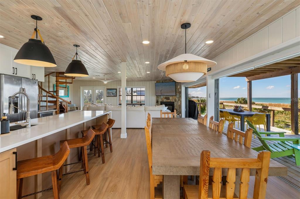 An open-concept kitchen and dining area with wood-paneled ceilings, a large island, and ocean views — 9498 ALBORADO ROAD, PLACIDA, FL