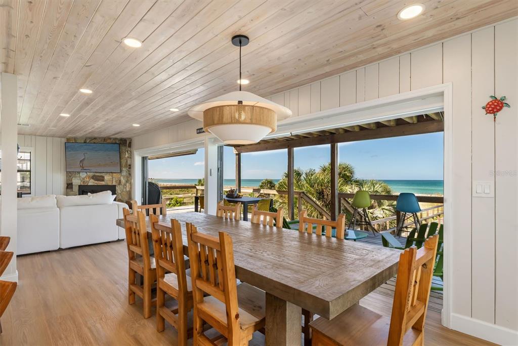 A dining room with a wooden table and chairs overlooks a deck and the ocean — 9498 ALBORADO ROAD, PLACIDA, FL