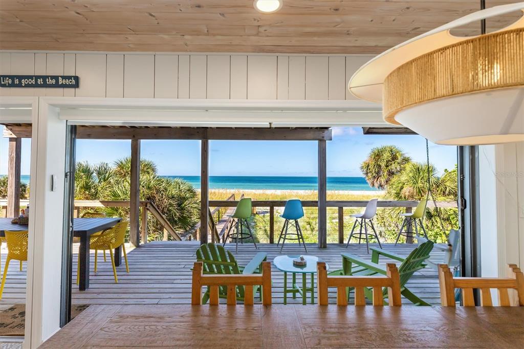 An open-concept dining area looks out onto a wooden deck with ocean views and seating — 9498 ALBORADO ROAD, PLACIDA, FL