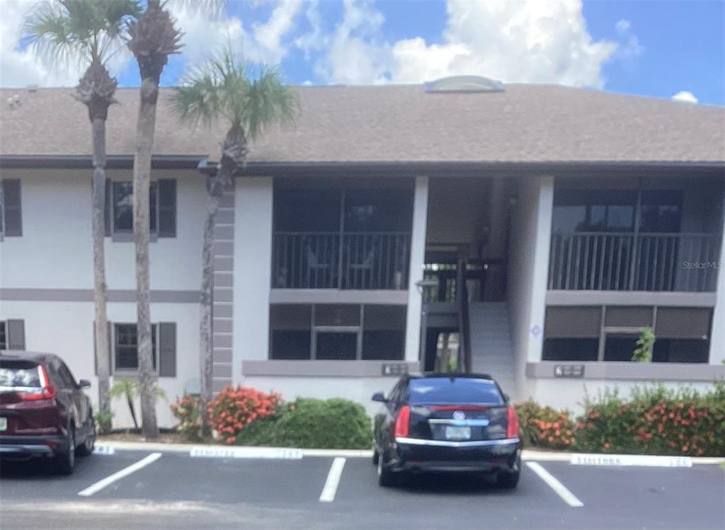 A two-story apartment building with screened balconies, palm trees, and a parking lot in front — 1515 FORREST NELSON BOULEVARD UNIT K106, PORT CHARLOTTE, FL
