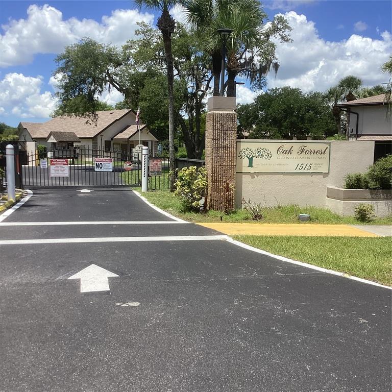 The gated entrance to a condominium complex features a brick pillar and a community sign — 1515 FORREST NELSON BOULEVARD UNIT K106, PORT CHARLOTTE, FL