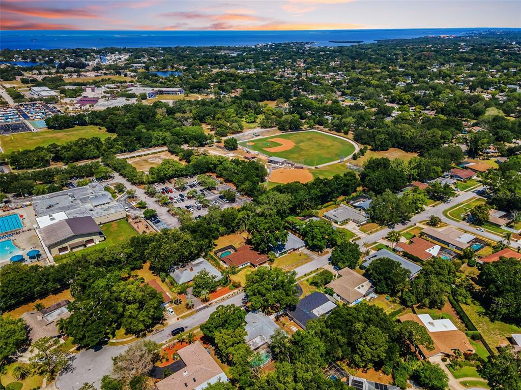 Aerial view of a residential neighborhood featuring a baseball field and a nearby parking lot — 520 SANDY HOOK ROAD, PALM HARBOR, FL