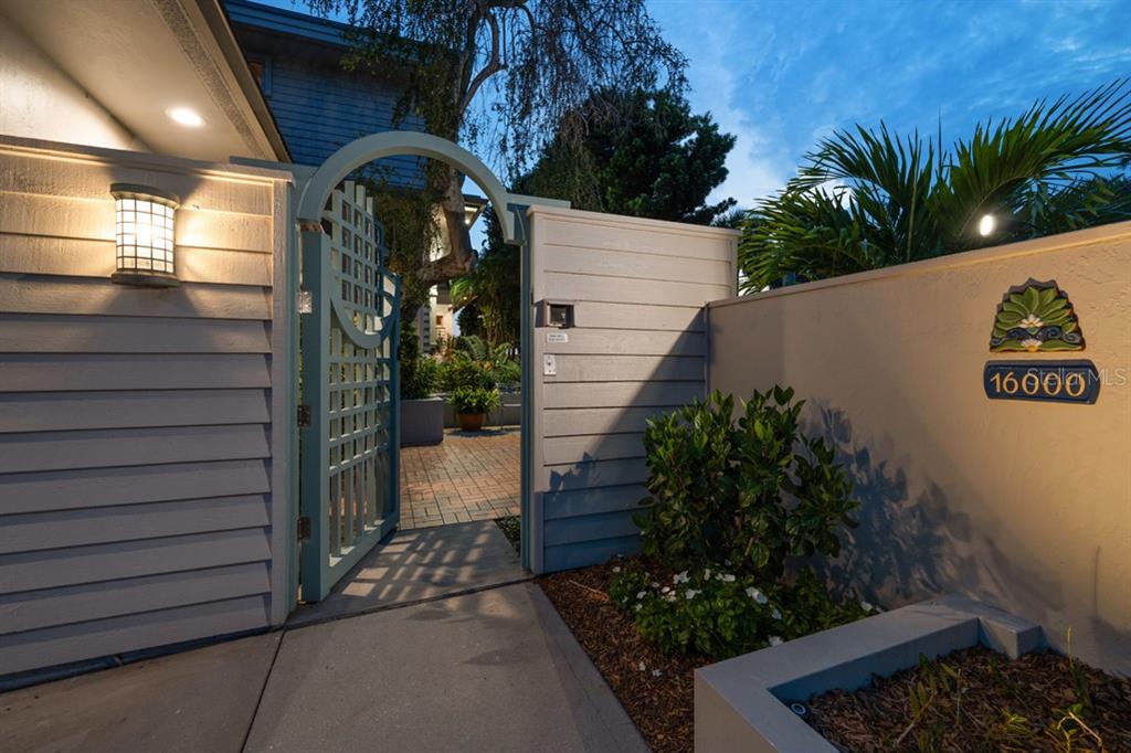 A light blue gate with an arched top leads to a paved courtyard entrance — 16000 GULF BOULEVARD, REDINGTON BEACH, FL
