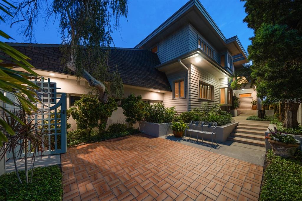 A paved courtyard leads to the entrance of a two-story house with horizontal wood siding — 16000 GULF BOULEVARD, REDINGTON BEACH, FL