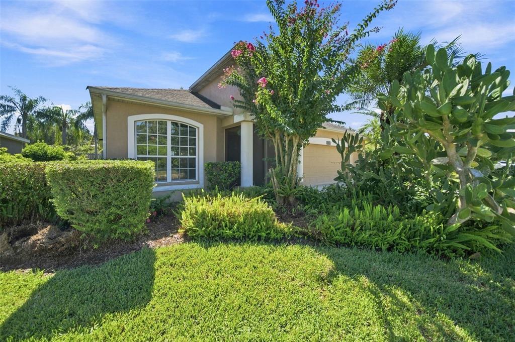 A single-story house with a tan exterior, a large arched window, and lush front landscaping — 295 LONDONDERRY DRIVE, SARASOTA, FL