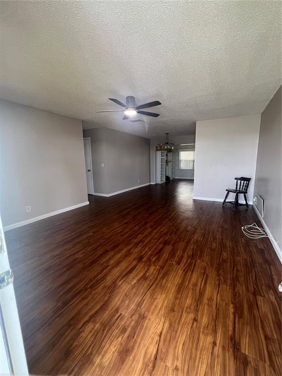 An empty living room features dark wood-look flooring, gray walls, and a ceiling fan — 4251 100TH AVENUE N, PINELLAS PARK, FL