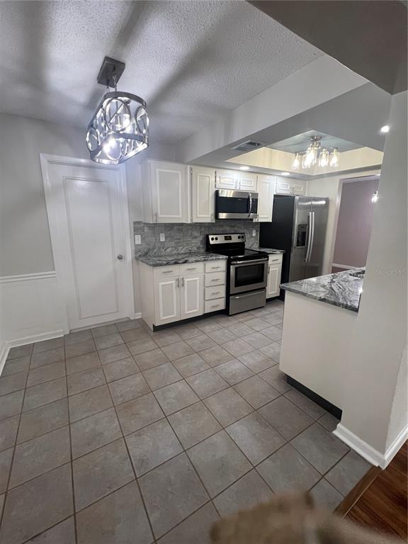 A kitchen with white cabinets, granite countertops, stainless steel appliances, and gray tile flooring — 4251 100TH AVENUE N, PINELLAS PARK, FL