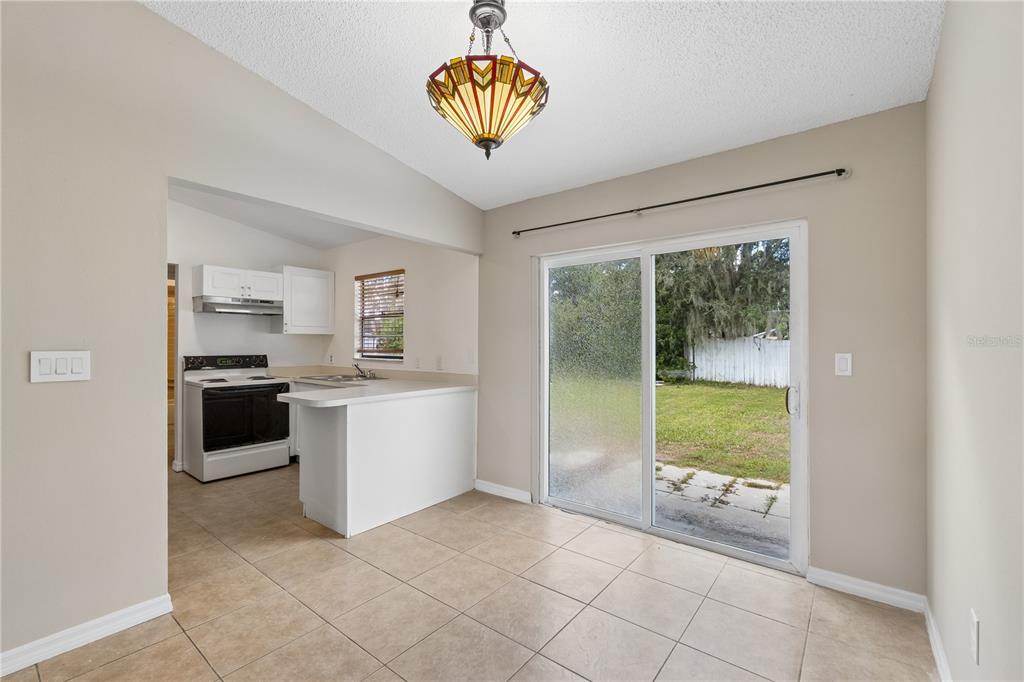 A living room with tan tile flooring, a grey accent wall, and a green sofa — 648 FLORIDIAN DRIVE, KISSIMMEE, FL