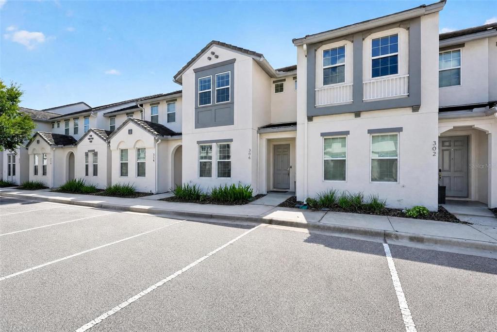 A row of multi-story townhouses with beige stucco siding and gray trim under a blue sky — 306 CAPTIVA DRIVE, DAVENPORT, FL