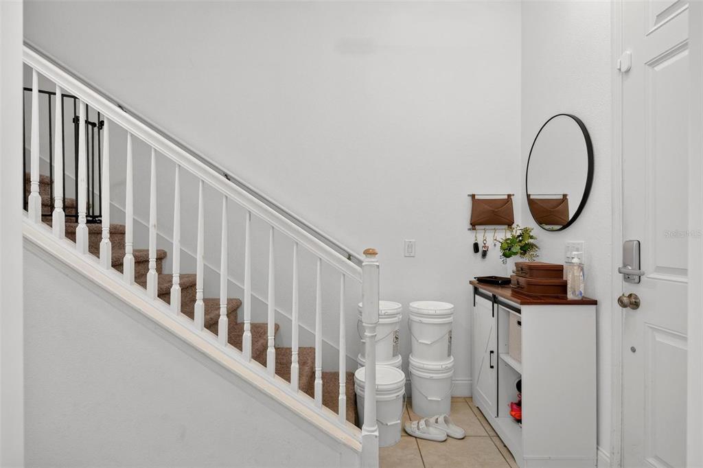 An entryway features a white staircase with a carpeted runner, tile flooring, and a console table — 306 CAPTIVA DRIVE, DAVENPORT, FL