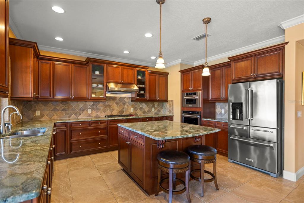 A kitchen features dark wood cabinets, granite countertops, a center island, and stainless steel appliances — 4165 MORENO DRIVE, PALM HARBOR, FL