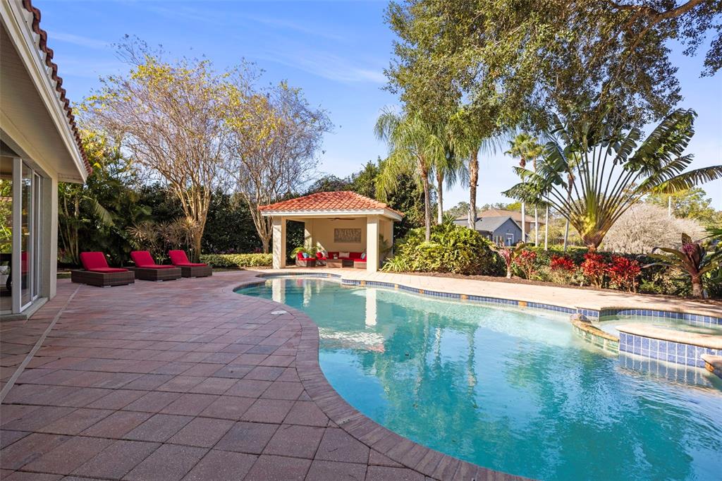A swimming pool and spa sit on a brick patio beside a covered outdoor pavilion — 4165 MORENO DRIVE, PALM HARBOR, FL