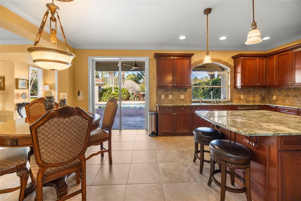 A kitchen and dining area with wood cabinets, granite countertops, and a sliding glass door — 4165 MORENO DRIVE, PALM HARBOR, FL
