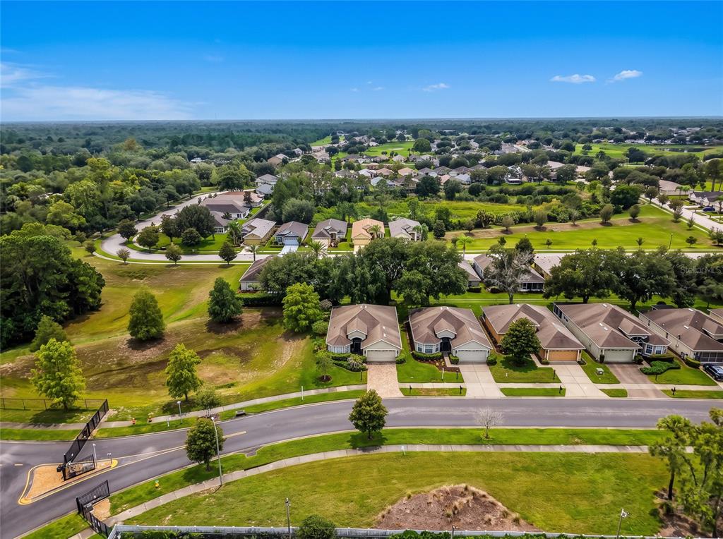 An aerial view shows a suburban neighborhood with houses, green lawns, and a gated entrance — 11916 HERITAGE POINT DRIVE, HUDSON, FL