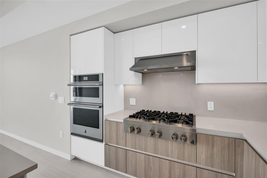A modern kitchen features white cabinetry, stainless steel appliances, and a large quartz-topped island — 400 CENTRAL AVENUE UNIT 3603, ST PETERSBURG, FL