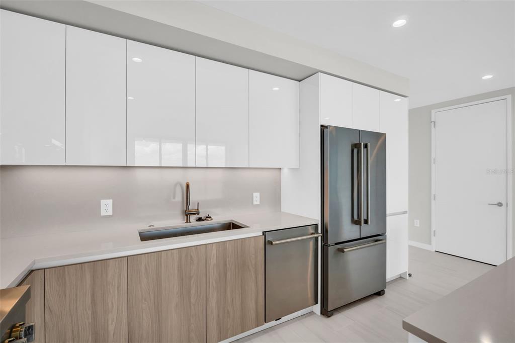 A modern kitchen features white upper cabinets, wood-tone lower cabinets, a gray island, and appliances — 400 CENTRAL AVENUE UNIT 3603, ST PETERSBURG, FL