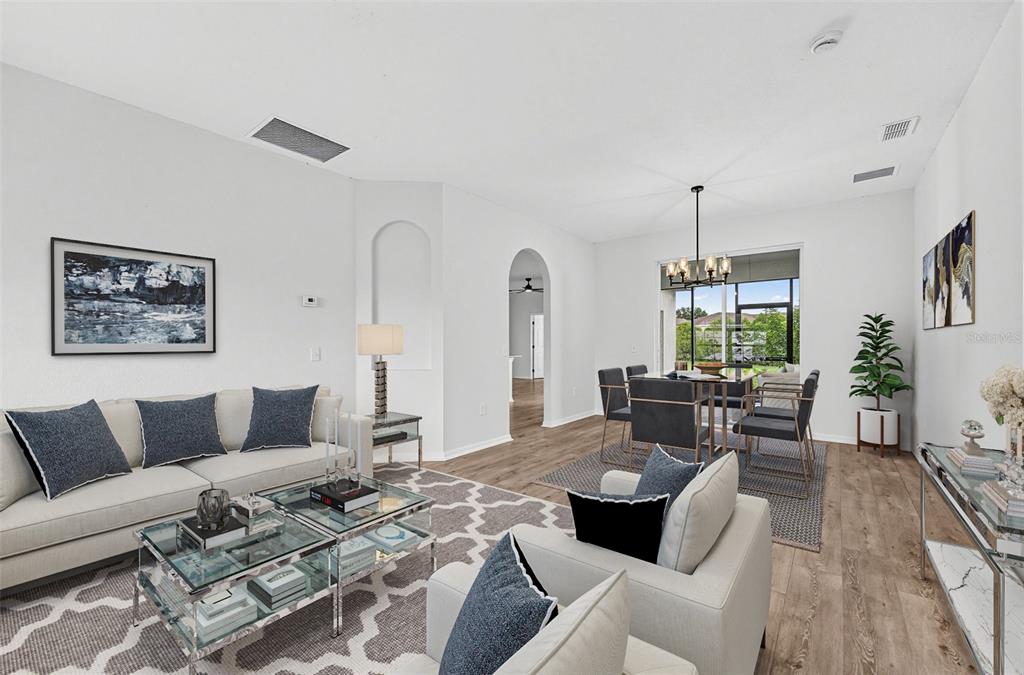 A bright living and dining area features white walls, wood-look flooring, and modern furniture — 507 BRITTEN DRIVE, KISSIMMEE, FL