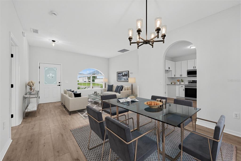 An open-concept living and dining area features light wood floors, a glass dining table, and kitchen — 507 BRITTEN DRIVE, KISSIMMEE, FL