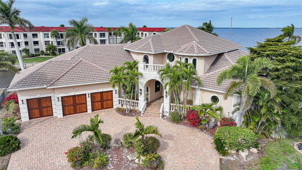 An aerial view of a two-story house with a tiled roof, brick driveway, and palm trees — 3 HIBISCUS DRIVE, PUNTA GORDA, FL