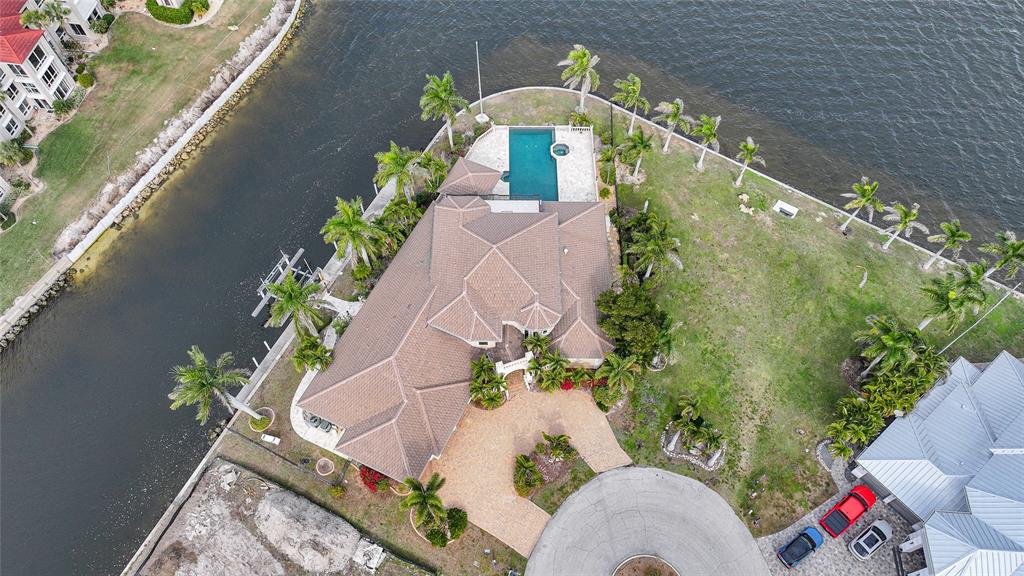 An aerial view shows a waterfront house with a pool, palm trees, and a driveway — 3 HIBISCUS DRIVE, PUNTA GORDA, FL