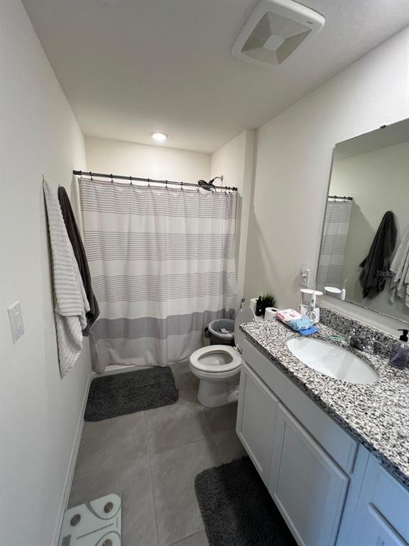 A bathroom features a granite vanity, a toilet, and a shower with a striped curtain — 2755 BRIE HAMMOCK BEND, HARMONY, FL