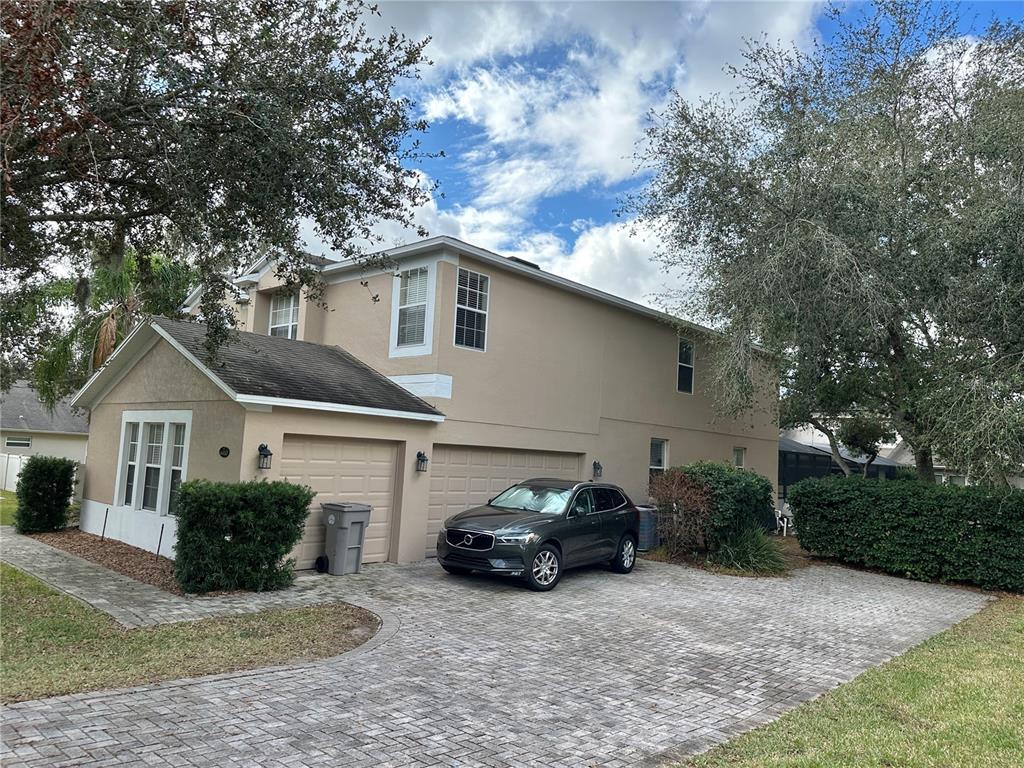 A two-story tan house with a paved driveway, a gray Volvo, and mature trees — 4410 PINE GOLD AVENUE, APOPKA, FL