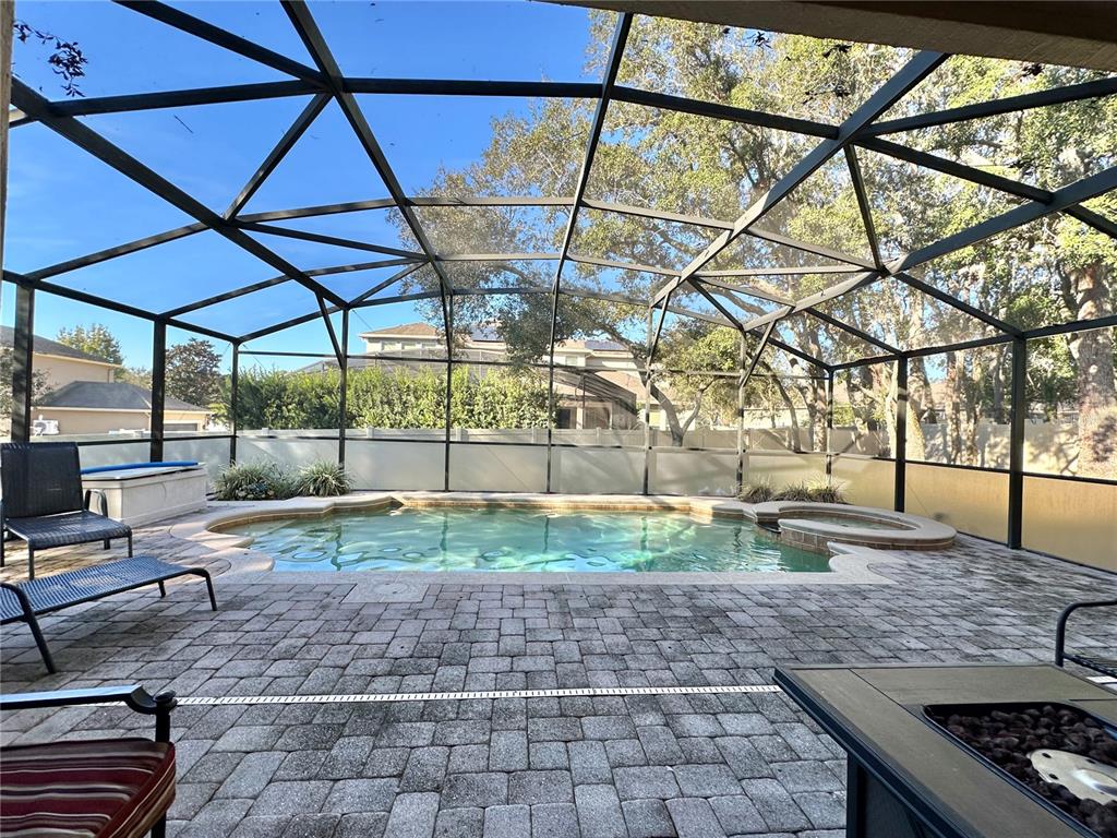 A screened-in patio features a swimming pool, spa, and paver flooring under a metal frame — 4410 PINE GOLD AVENUE, APOPKA, FL