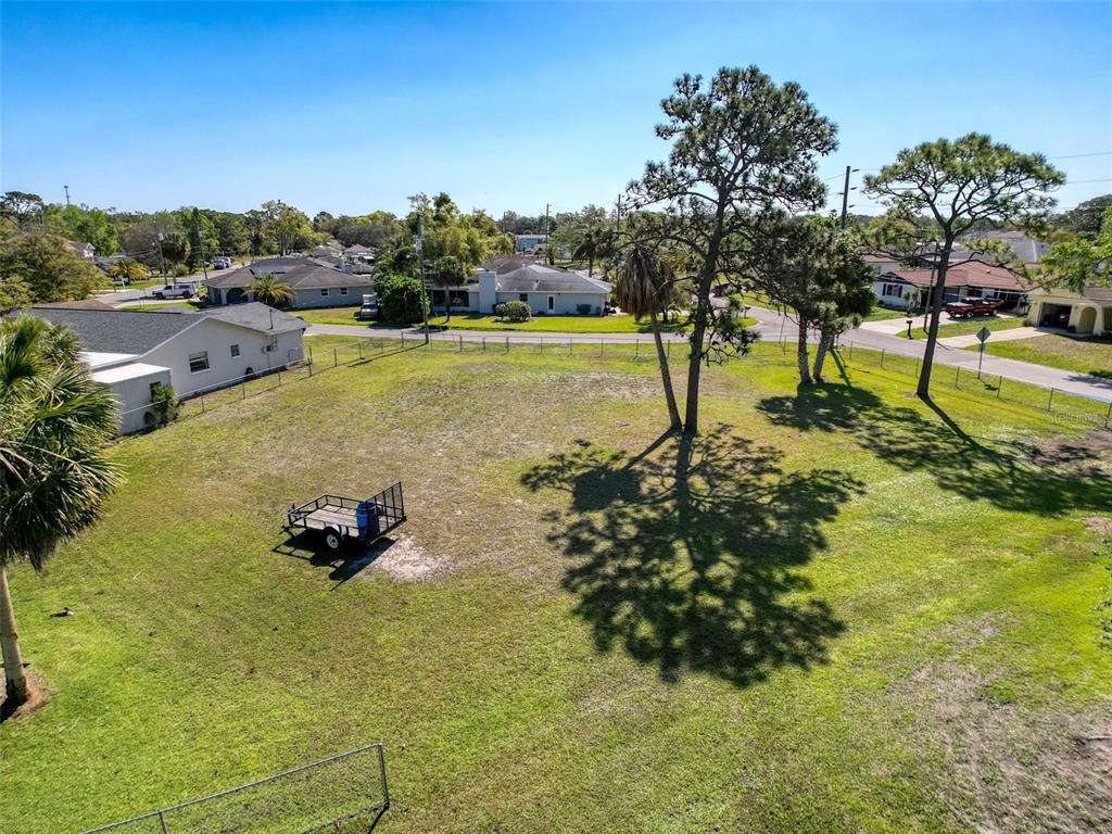 An aerial view shows a grassy residential lot with two large pine trees and a trailer — INDIES DRIVE, HUDSON, FL