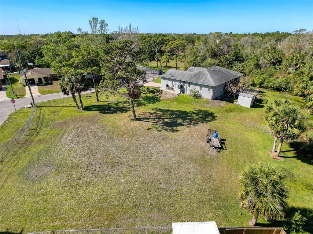 An aerial view shows a large grassy backyard with several trees and a single-story house — INDIES DRIVE, HUDSON, FL