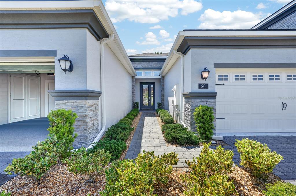 A paved walkway leads to the front entrance between two garage sections of a house — 20 LONGRIDGE LANE, ORMOND BEACH, FL