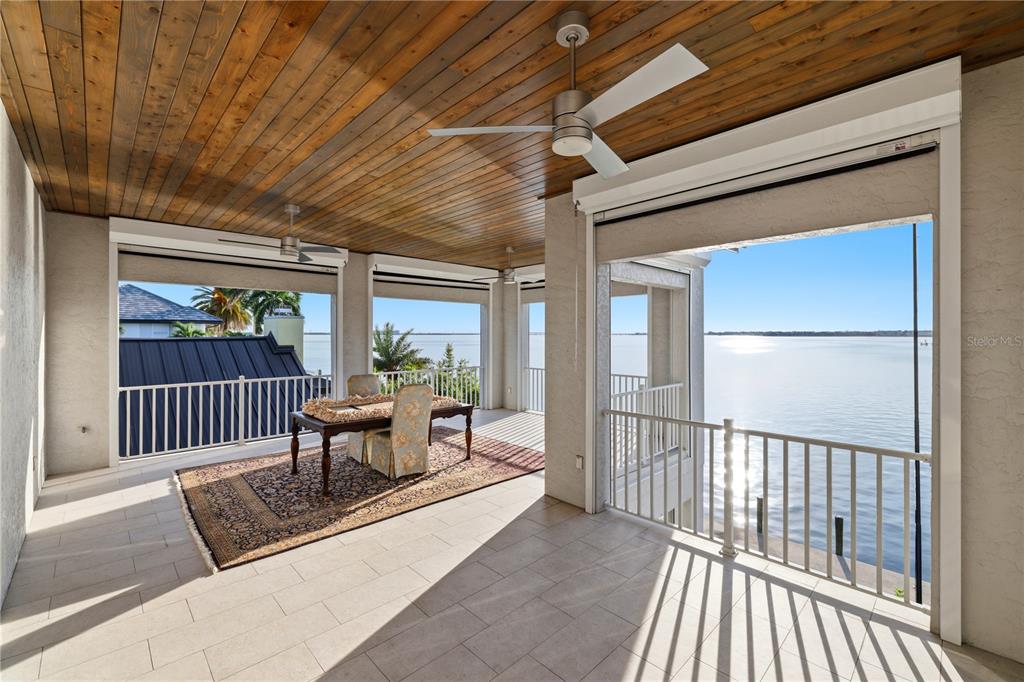A covered patio features a wood-paneled ceiling, ceiling fans, and views of a waterfront canal — 2139 PALM TREE DRIVE, PUNTA GORDA, FL