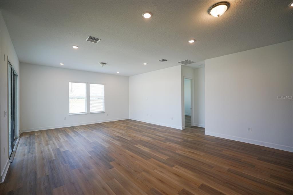 An empty living room features white walls, recessed lighting, and wood-look vinyl plank flooring — 1 BLUE GROTTO PLACE, PALM COAST, FL