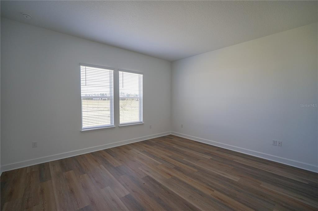 An empty bedroom features white walls, wood-look flooring, and two windows with blinds — 1 BLUE GROTTO PLACE, PALM COAST, FL