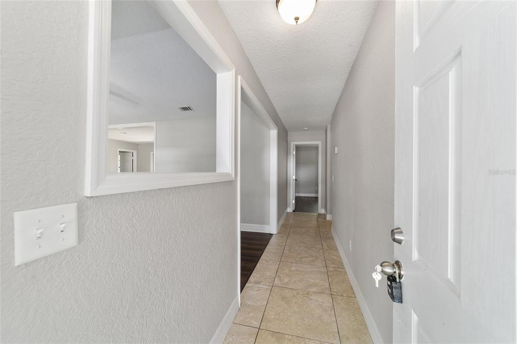 A hallway with tile flooring leads to a doorway, featuring a wall cutout and light fixture — 35 PINE CIRCLE, OCALA, FL