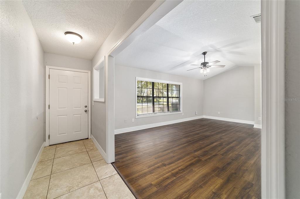 An entryway with tile flooring leads into a living room featuring wood-look floors — 35 PINE CIRCLE, OCALA, FL