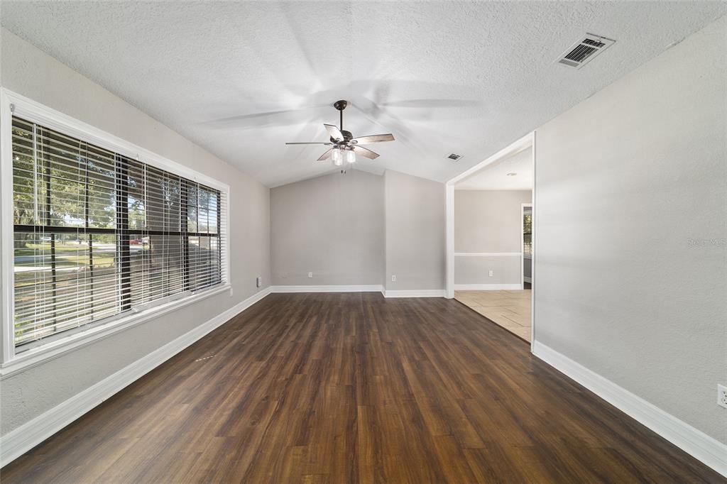 An empty room with wood-look flooring, a vaulted ceiling, and a ceiling fan — 35 PINE CIRCLE, OCALA, FL