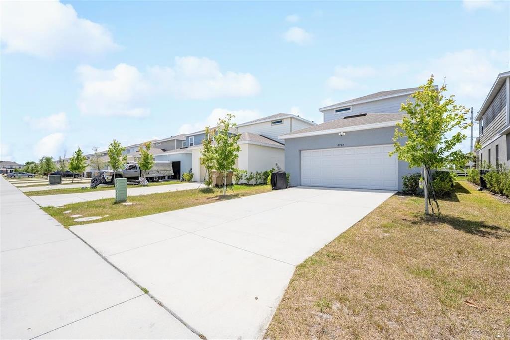 A suburban street view showing a row of modern houses with concrete driveways and lawns — 2769 FRANKLIN ROAD, ST CLOUD, FL