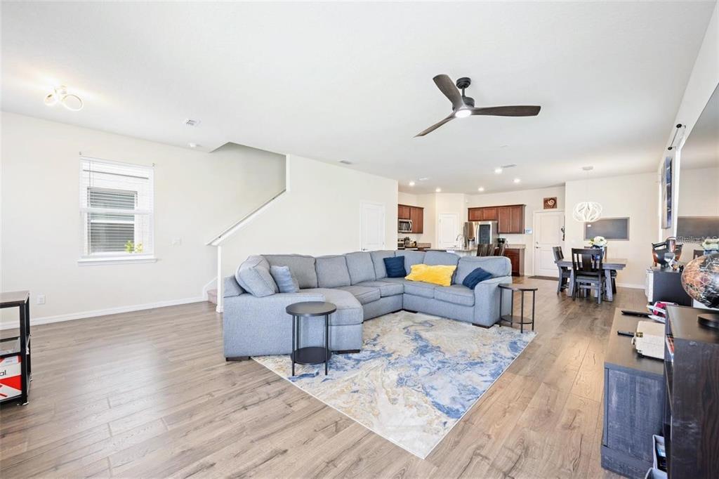 An open-concept living room features a gray sectional sofa, wood-look flooring, and a ceiling fan — 2769 FRANKLIN ROAD, ST CLOUD, FL