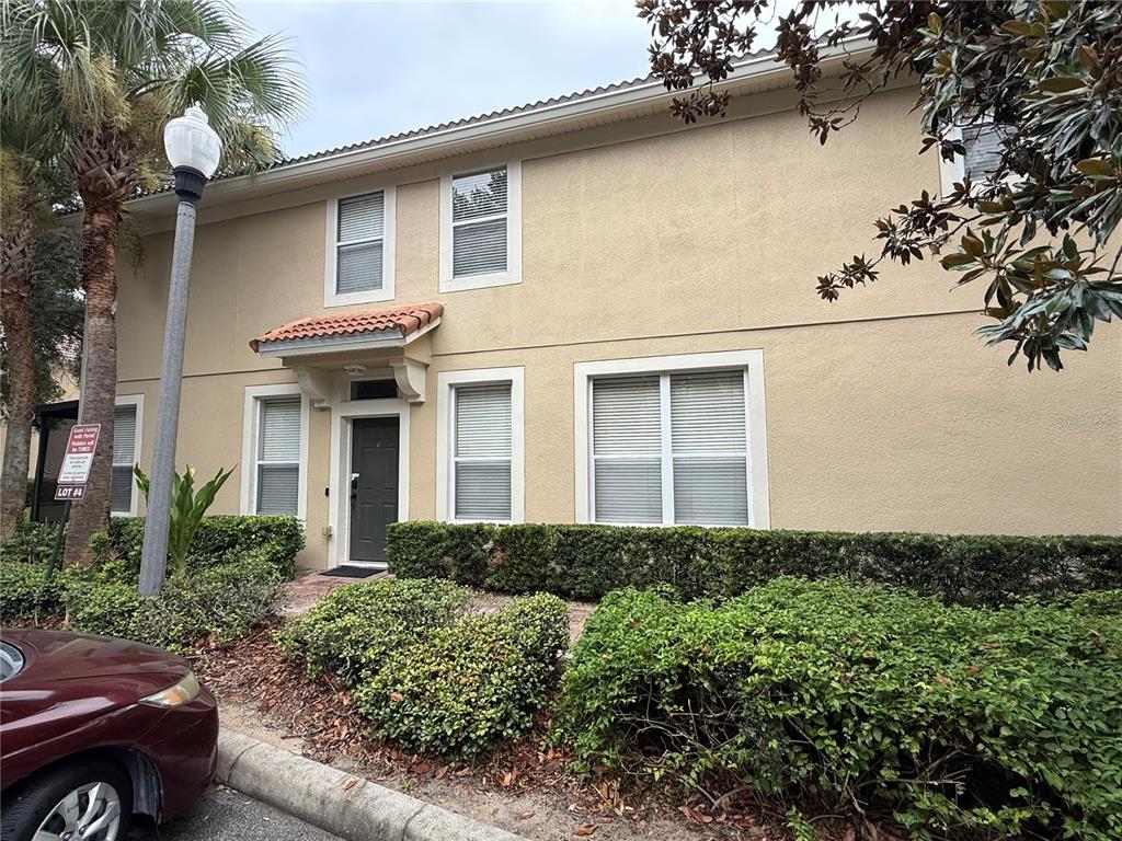 A two-story tan stucco building with a tiled entryway and a landscaped front yard — 6485 RANELAGH DRIVE UNIT 101, ORLANDO, FL