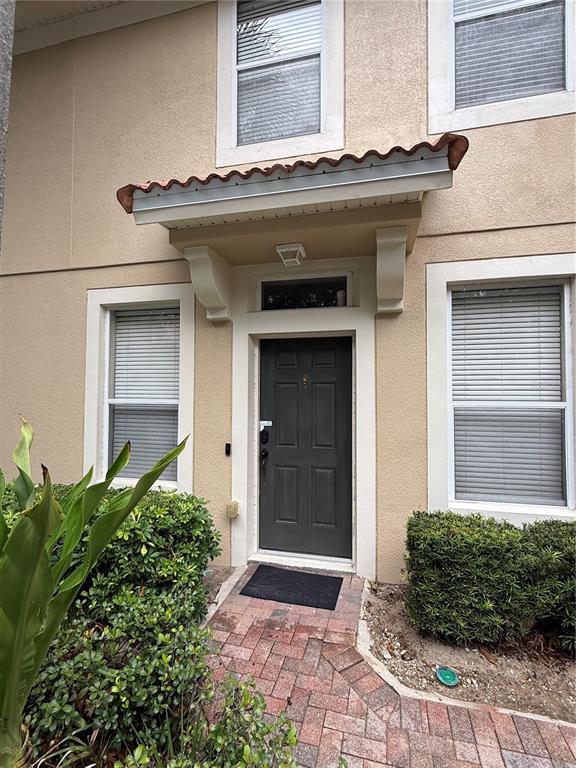 The exterior of a tan building features a dark front door under a small tiled awning — 6485 RANELAGH DRIVE UNIT 101, ORLANDO, FL