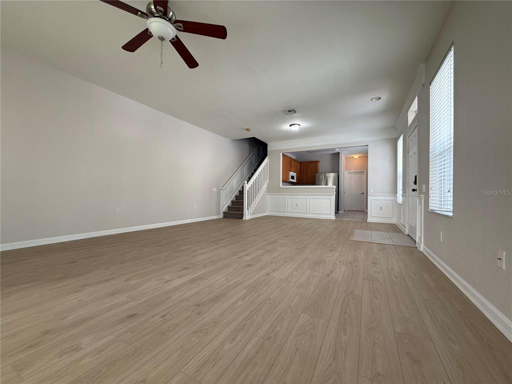 An open living area features wood-look flooring, a white staircase, and sliding glass patio doors — 6485 RANELAGH DRIVE UNIT 101, ORLANDO, FL